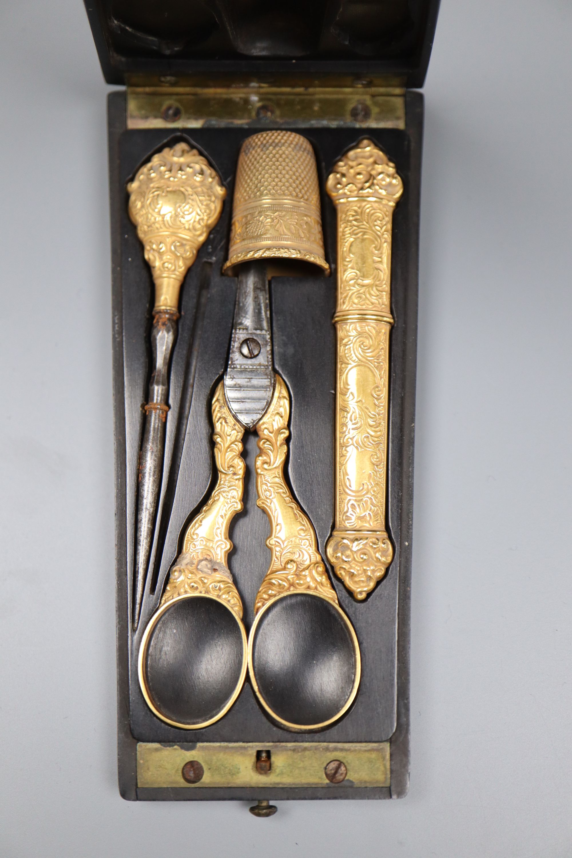 A cased 19th century French yellow metal three piece necessaire, with later associated metal thimble,